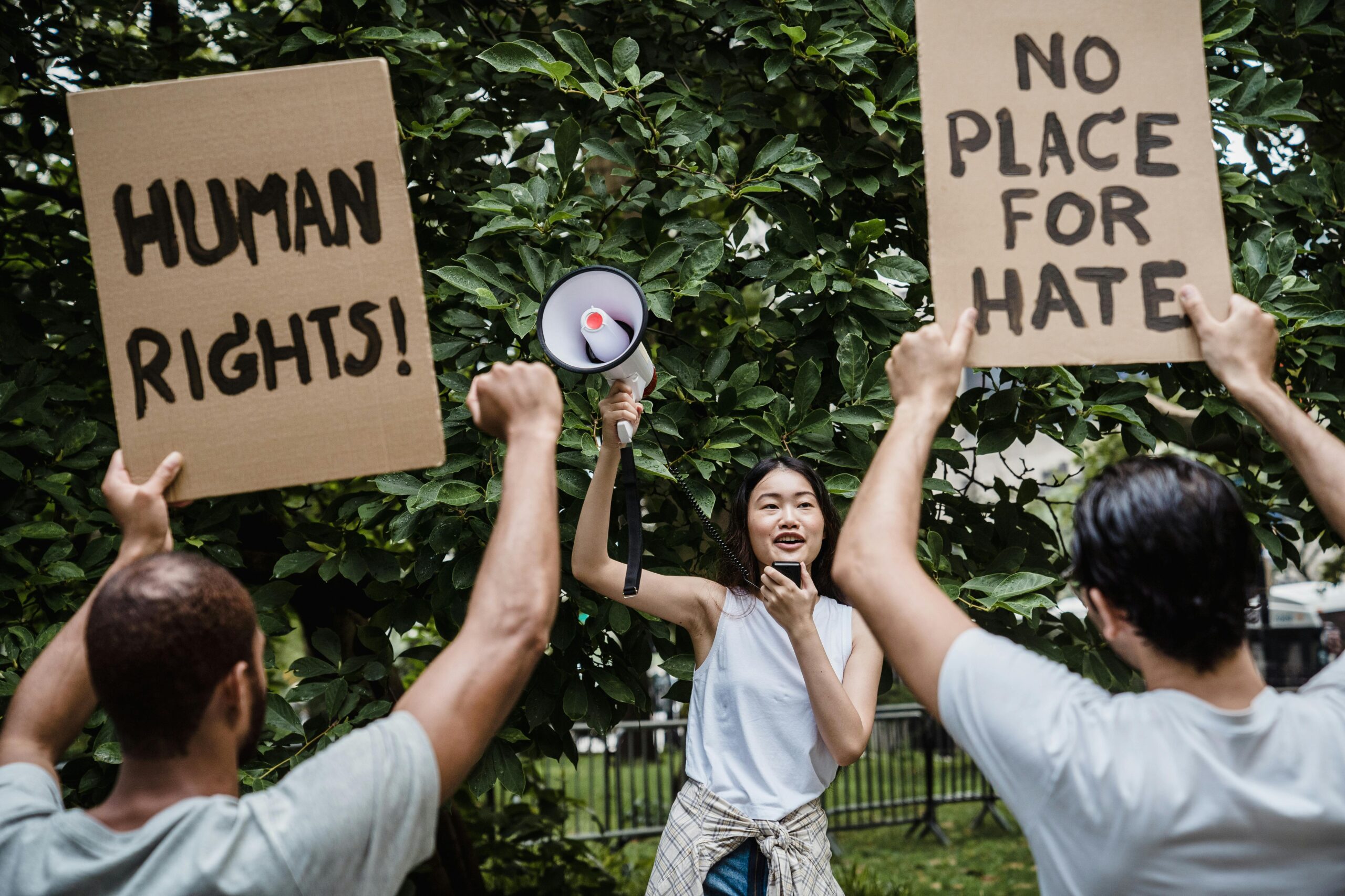 A diverse group of people protesting with signs advocating for human rights and against hate.